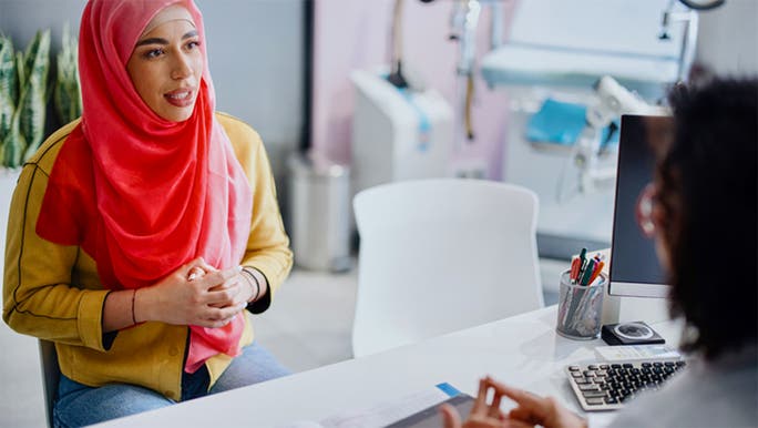 A woman wearing a red head scarf is having a medical consultation